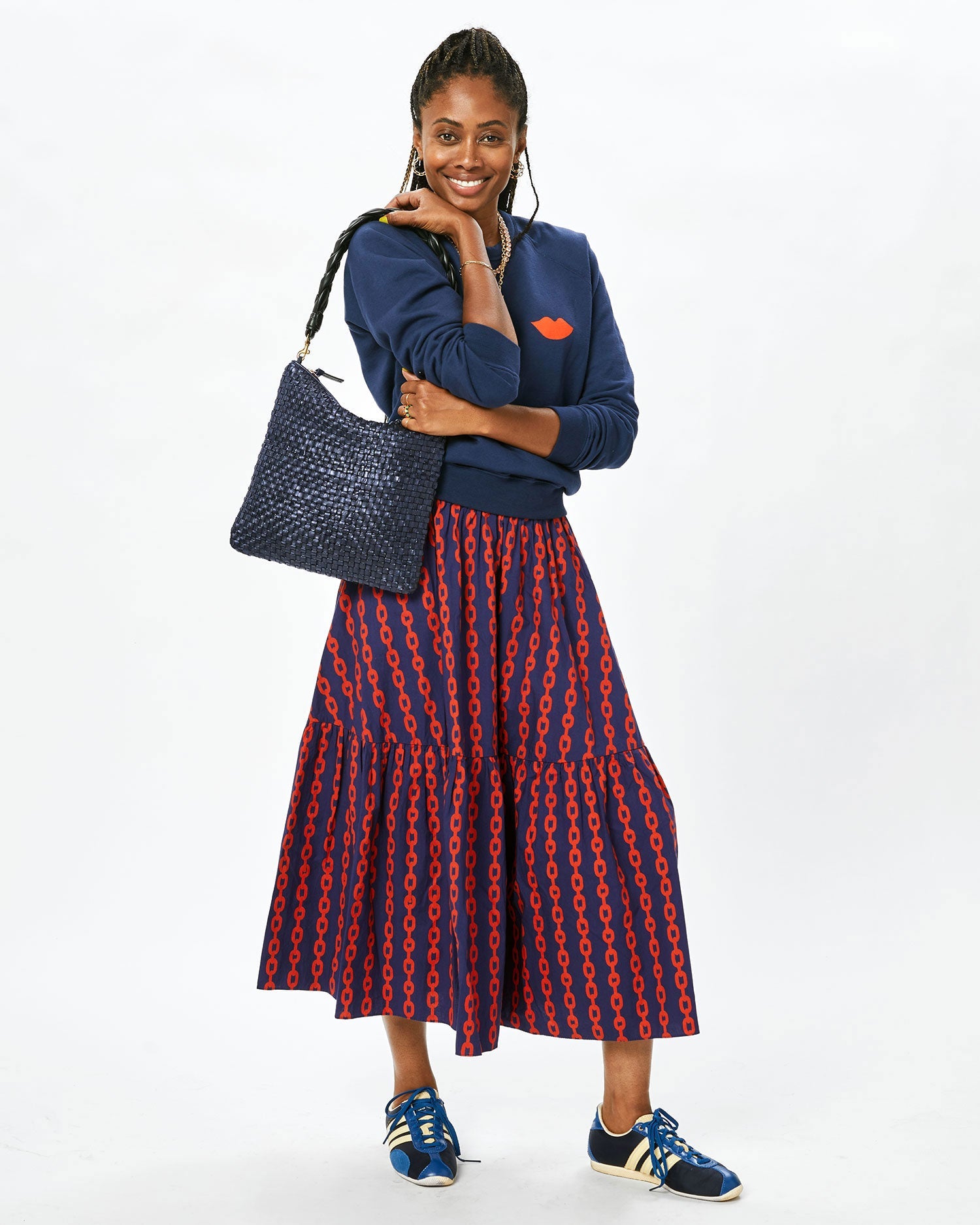 Mecca with the Twilight Foldover Clutch w/ Tabs on her shoulder in the Manon Skirt and the navy with lips sweatshirt