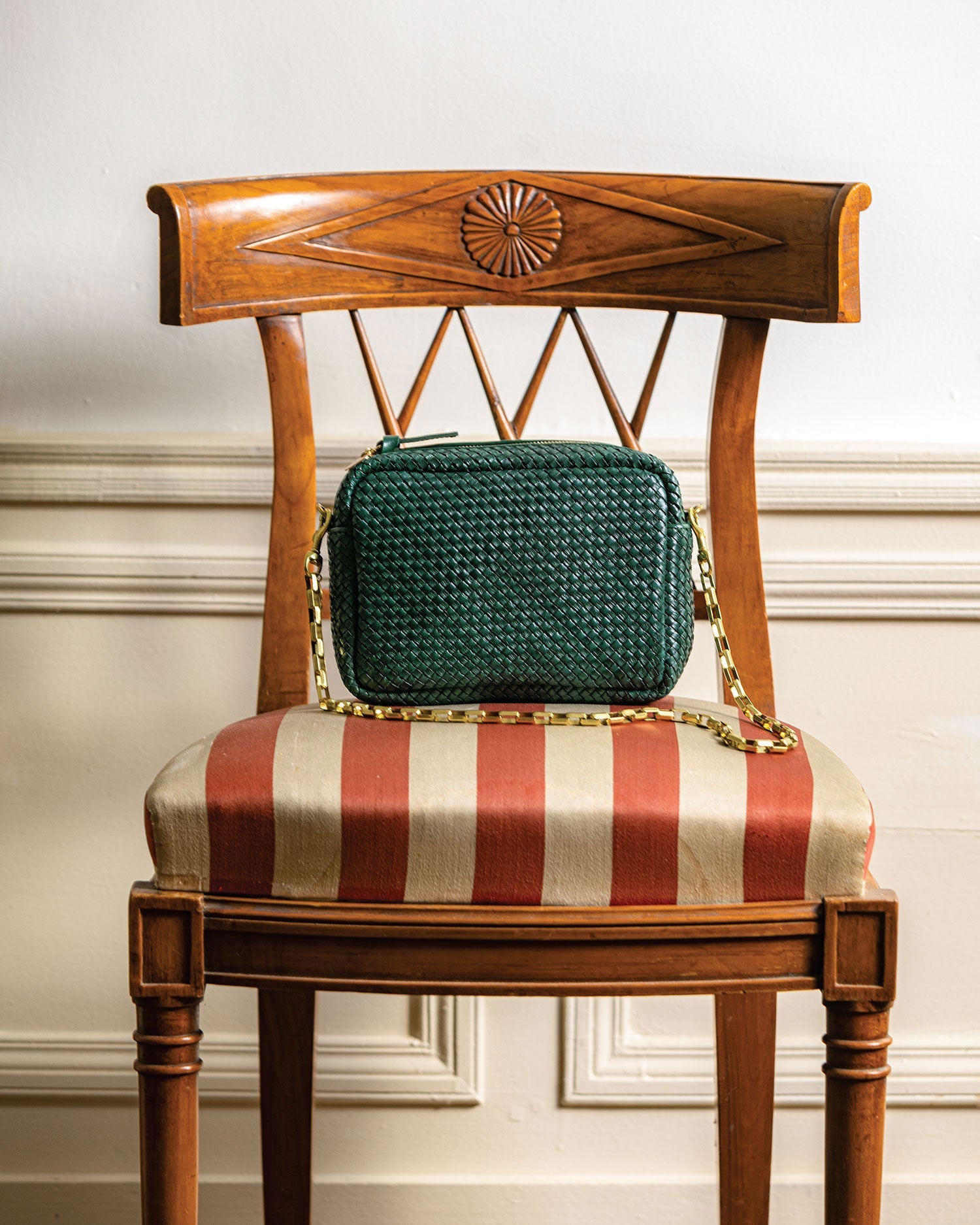 Deep Sea Woven Midi Sac sitting on a chair with the brass box chain shoulder strap attached