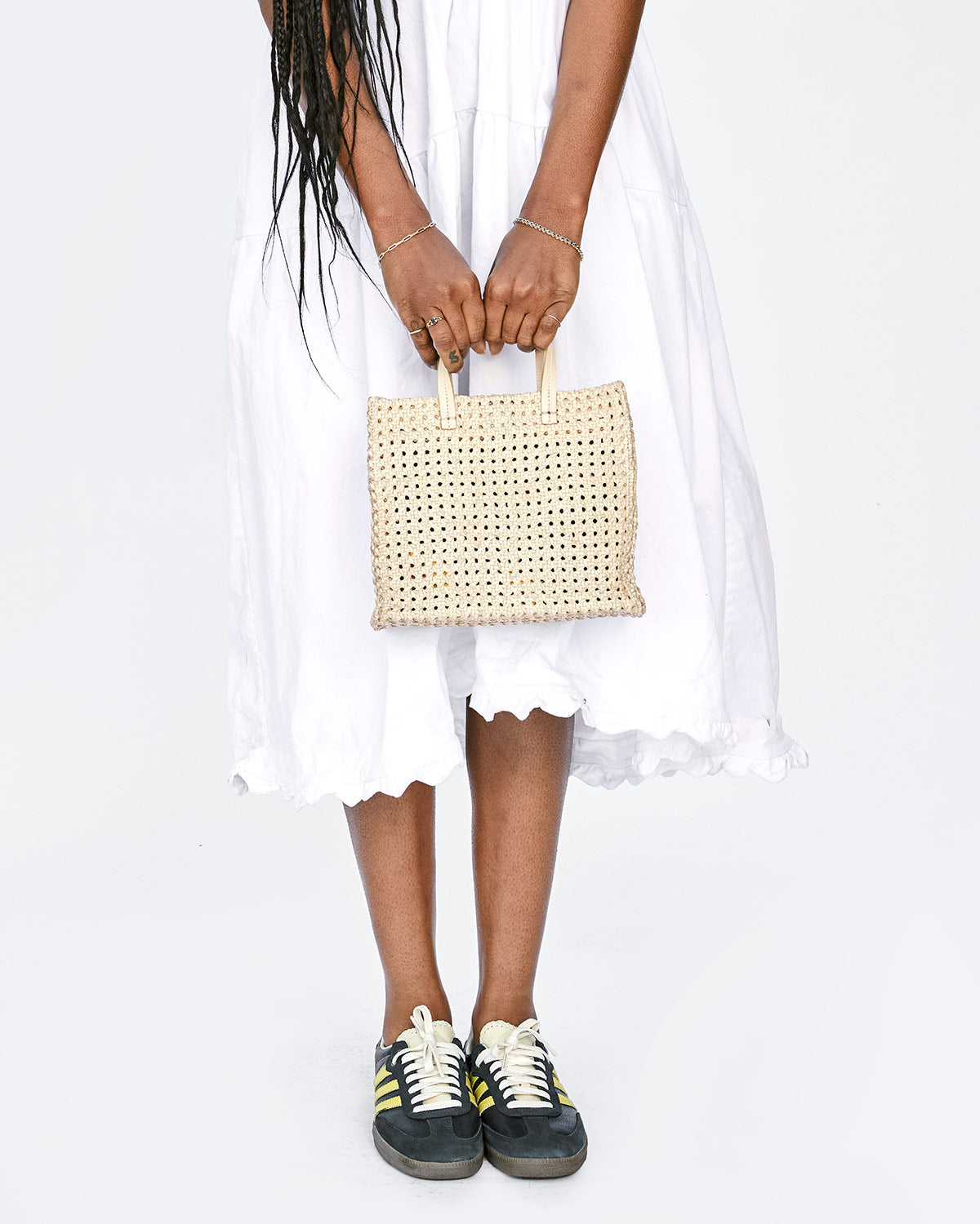 Mecca Holding the Cream Rattan Petit Simple Tote in Front of her White Dress