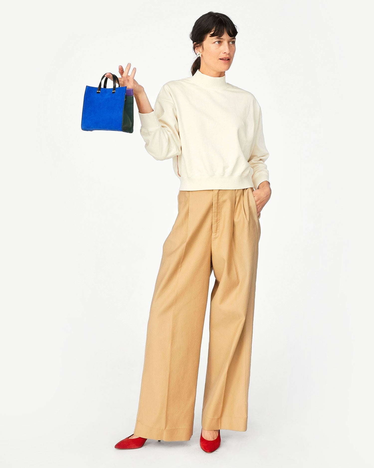 Danica wearing the Cream Le Drop Turtleneck with Khaki colored wide leg pants and holding our Electric Blue Simple Tote Bebe